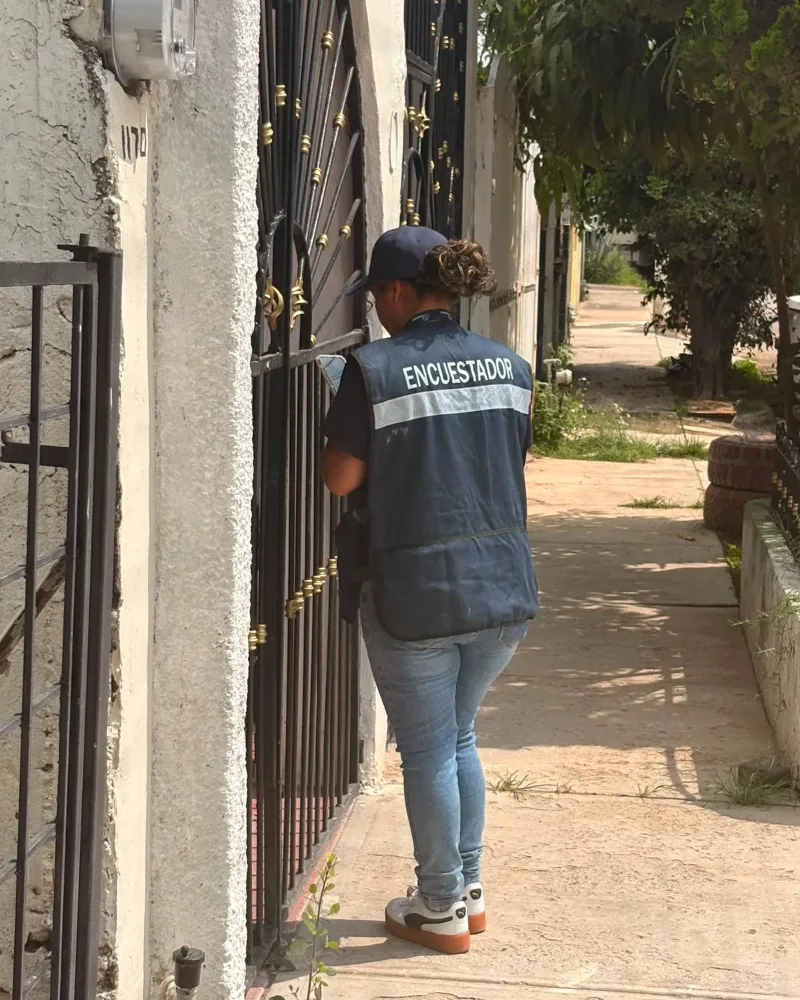 Encuestadora de CENESSOD registrando una entrevista efectiva en el zaguán de un hogar.