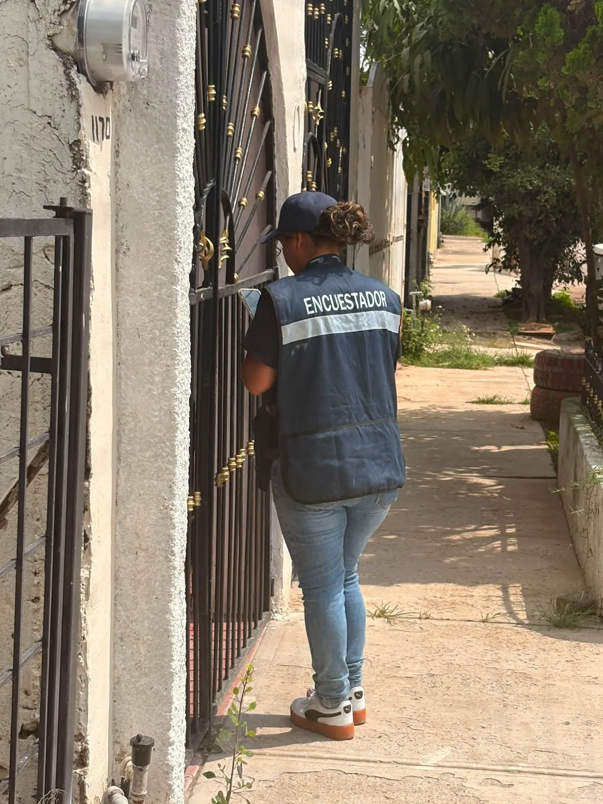 Encuestadora de CENESSOD registrando una entrevista en el zaguán de una vivienda.